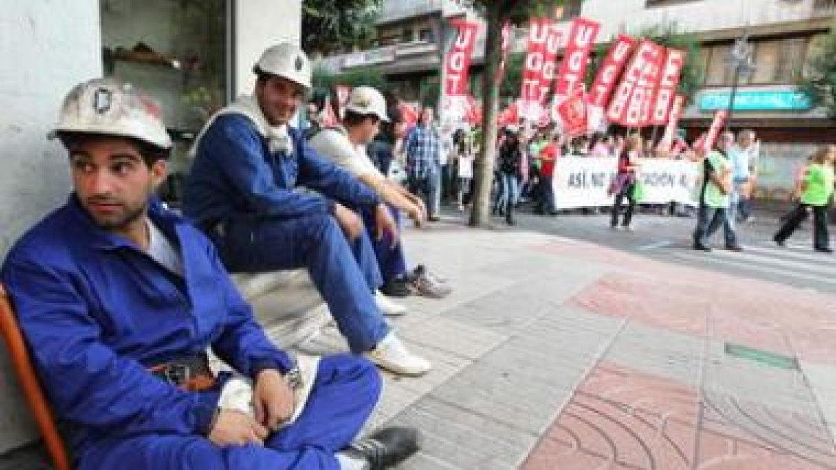 Varios mineros sentados, al paso de la manifestación de la huelga general.