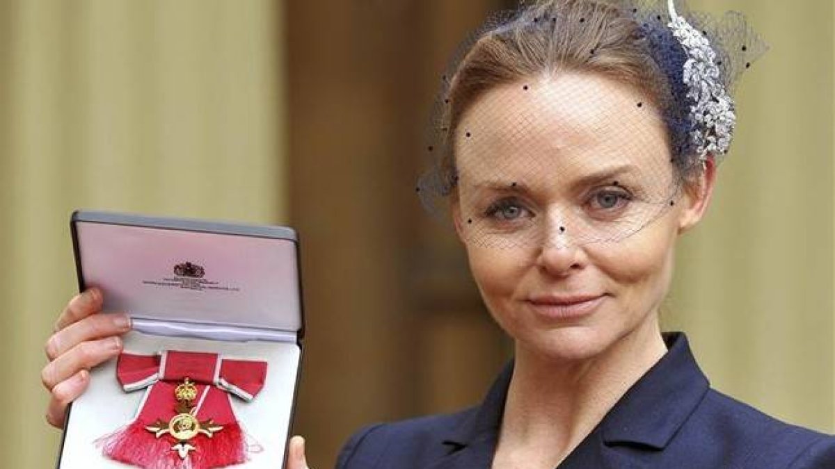 La diseñadora Stella McCartney muestra la medalla tras recibir el título oficial de la Orden del Imperio Británico.