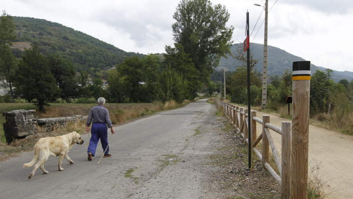 Un hombre camina con su perro por la Vía Verde de Laciana, en el Reserva de la Biosfera del Valle de Laciana. JESÚS F. SALVADORES