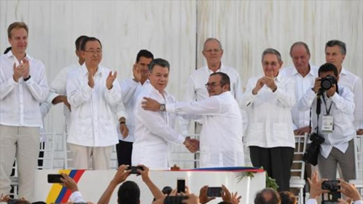 Santos y Timochenko se dan la mano entre los aplausos de Ki-mon, Castro y el rey emérito Juan Carlos, entre otras personalidades.