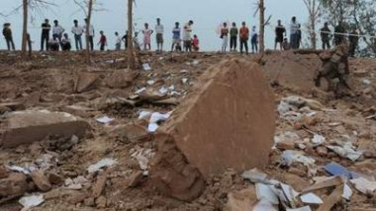 Varios curiosos observan el hoyo causado por la explosión.