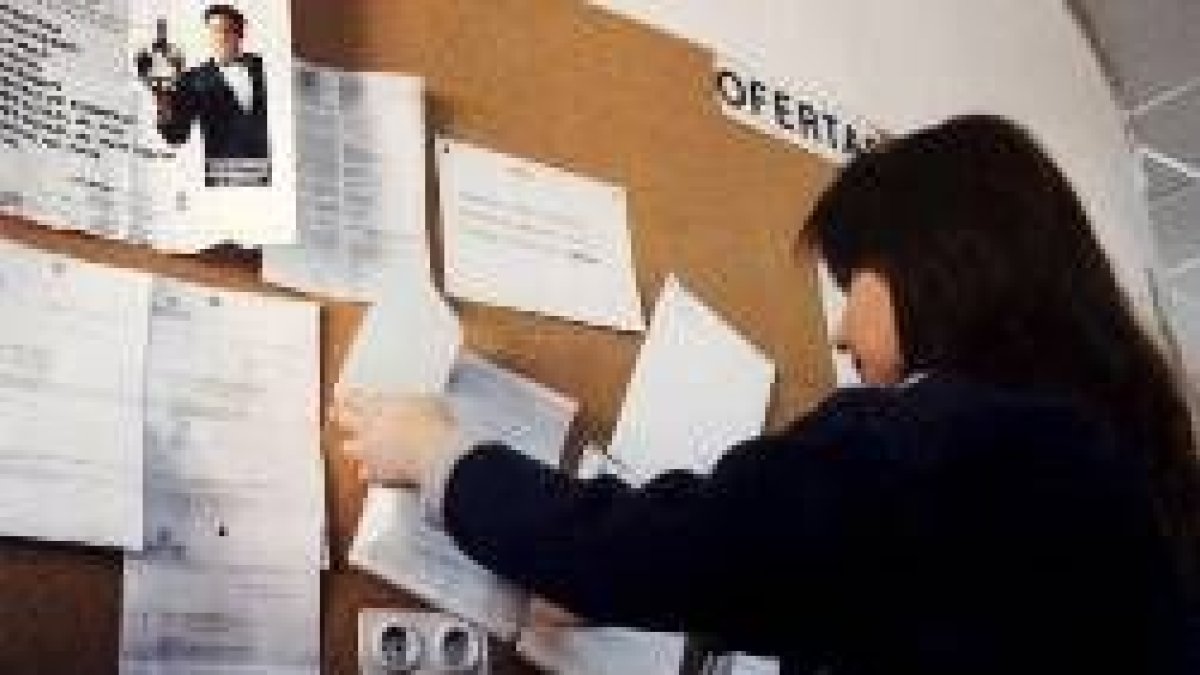 Una joven mira las ofertas de empleo en un tablón de anuncios de una oficina del Inem