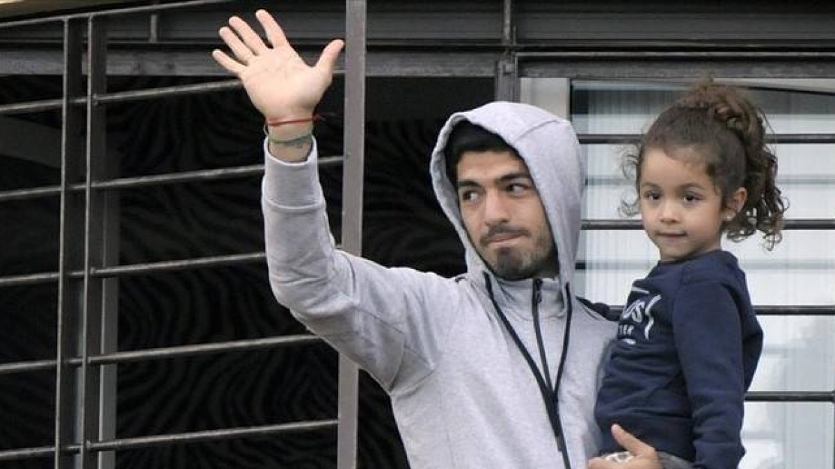 Luis Suárez saluda a los aficionados uruguayos desde el balcón de su casa con su hija.