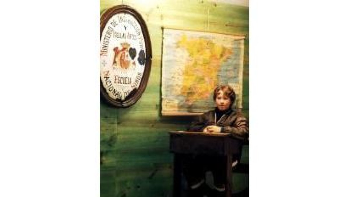 Un niño en un pupitre antiguo junto a un mapa político de España