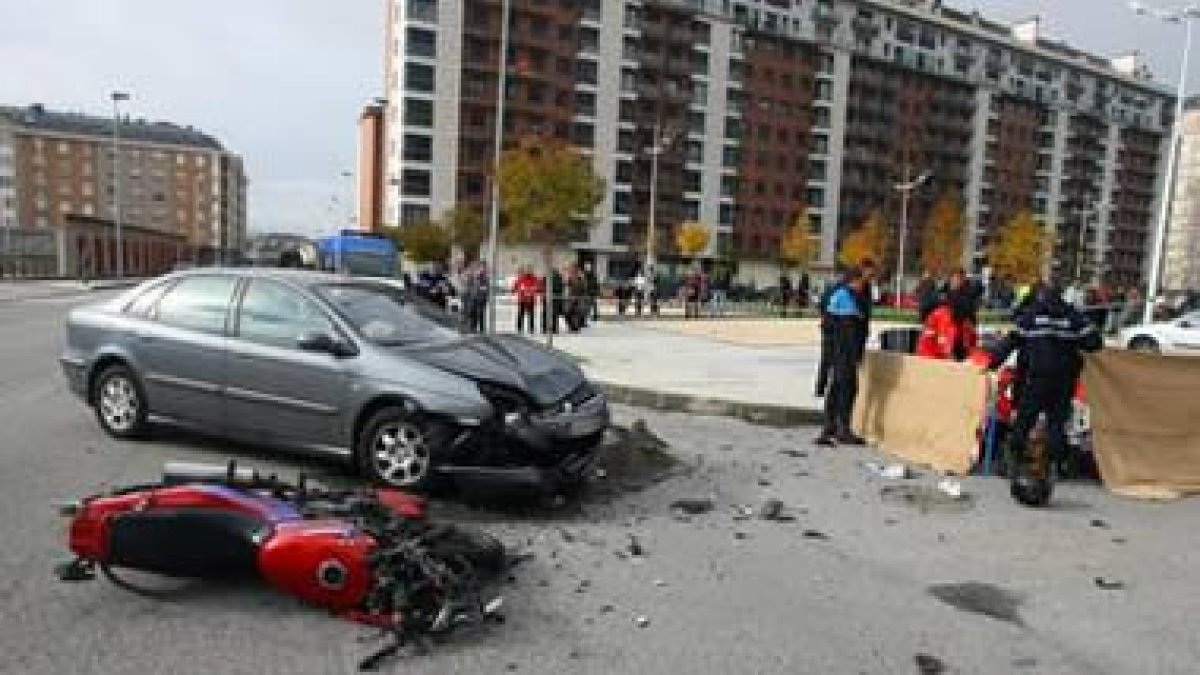 La motocicleta y el automóvil en primer plano, con las asistencias atendiendo al fallecido.