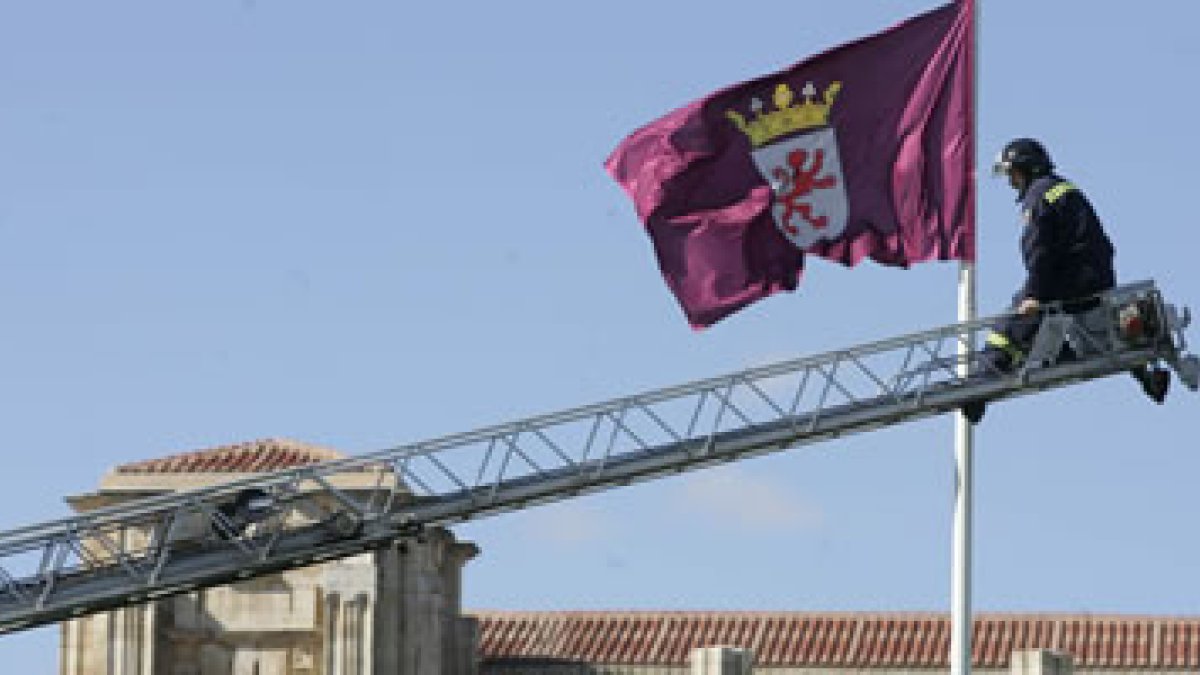 Un bombero coloca una bandera de León en el edificio de la Junta