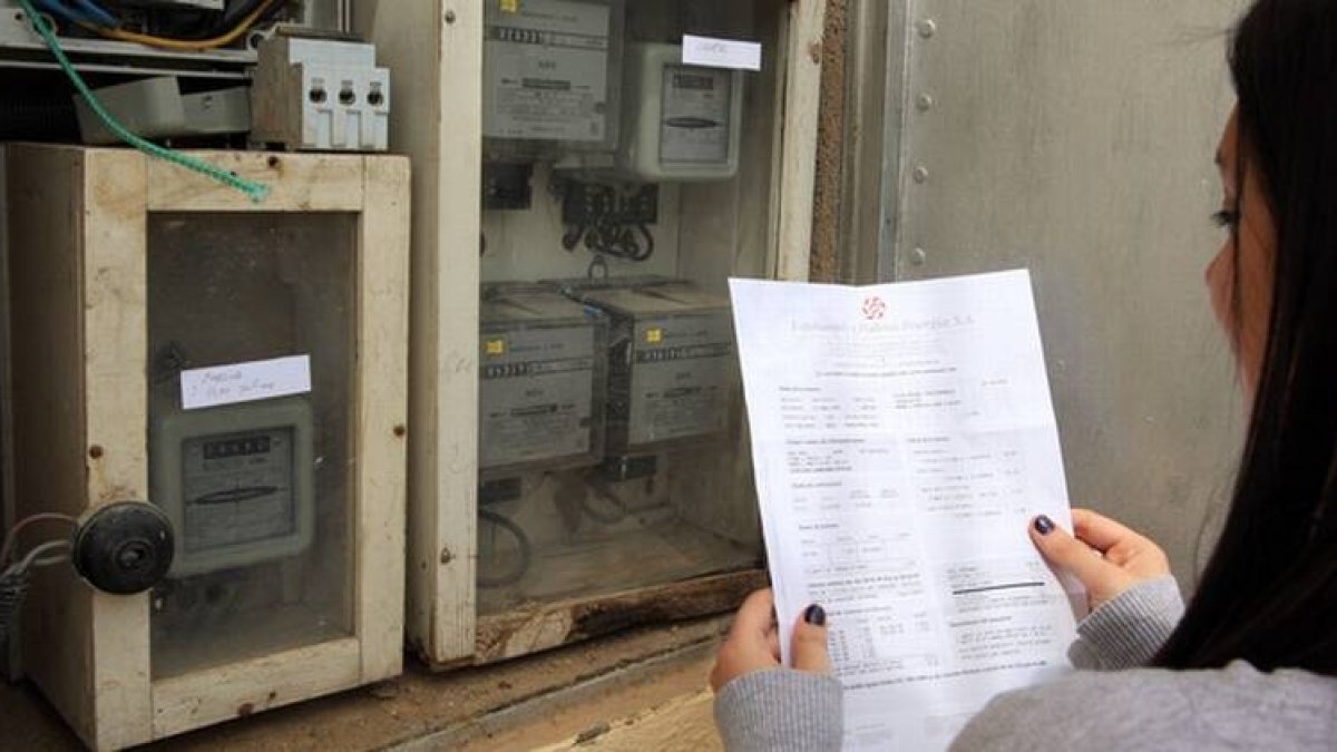 Una usuaria comprueba el contador de la luz con su factura.