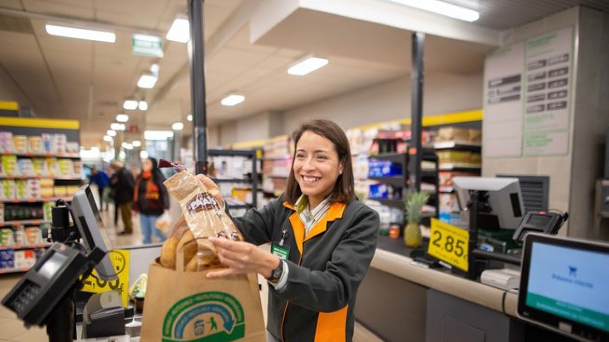 Una cajera de Mercadona deposita la compra en una bolsa de papel.