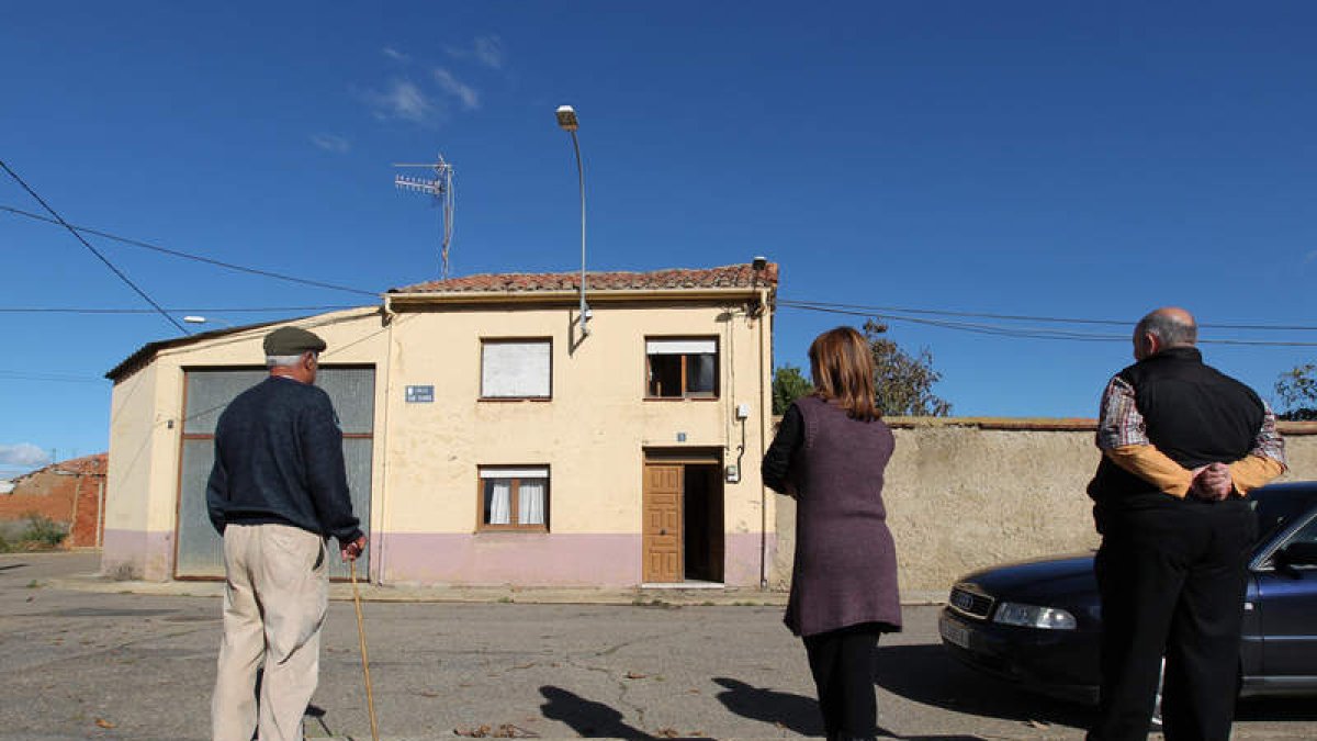 Varios vecinos contemplan la vivienda incendiada el lunes.
