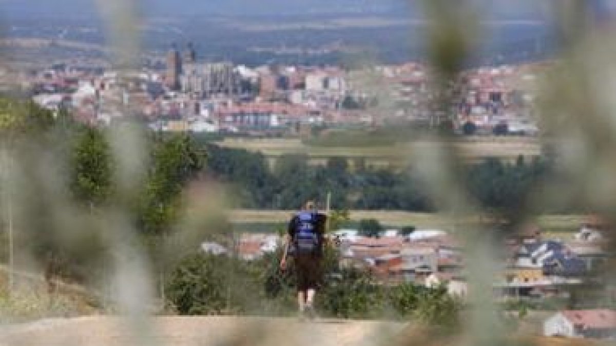 Una peregrina se aproxima a Astorga en uno de los meses de verano.