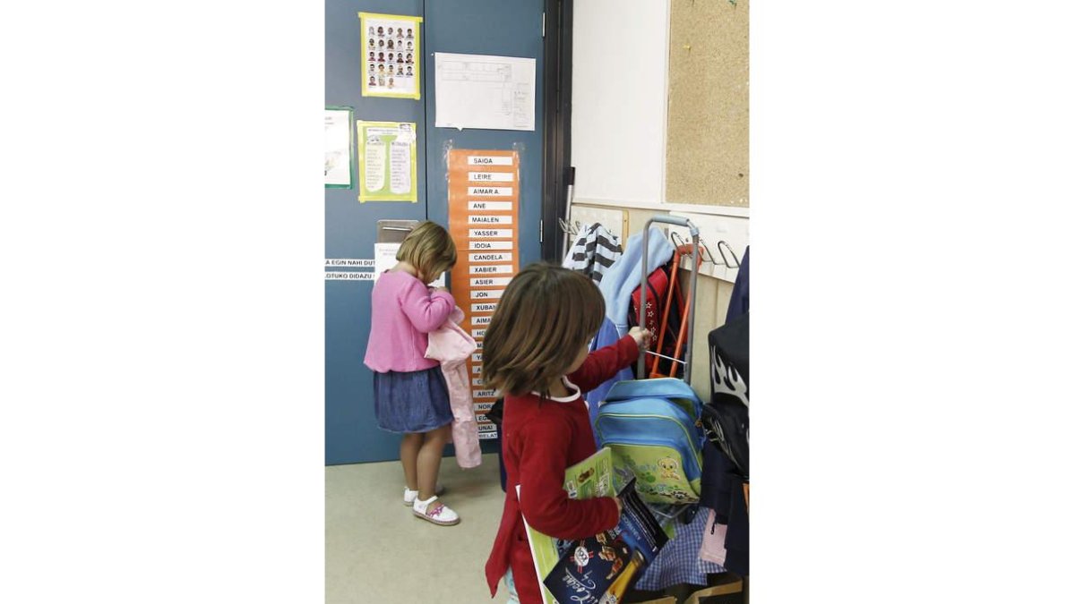 Dos niñas colocan sus mochilas al llegar a clase.