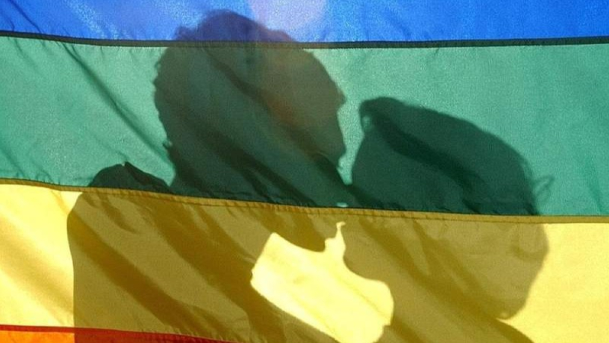 Una pareja velada por la bandera arcoíris en un acto del día del Orgullo LGTBIQ+. JESUS F. SALVADORES