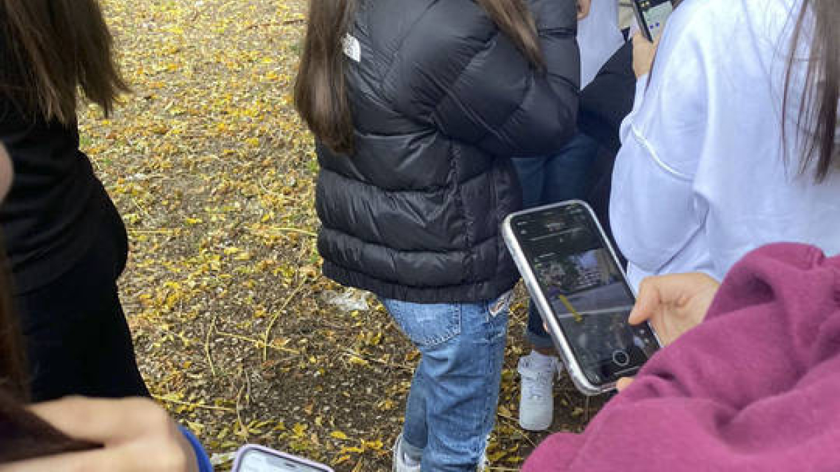 Varios jóvenes usan el móvil en el colegio.