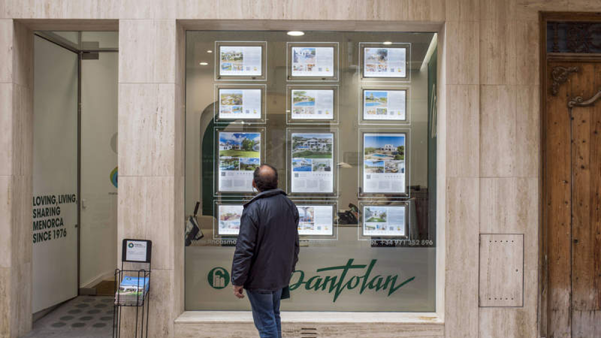 Un hombre mira el escaparate de una inmobiliario en Menorca.. DAVID ARQUIMBAU SINTE