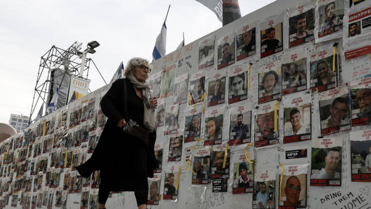 Una mujer israelí pasa junto a un muro con imágenes.