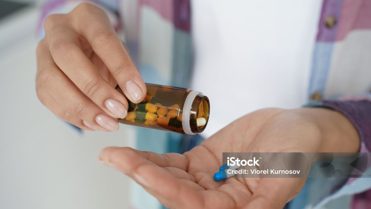 Una mujer con un frasco de pastillas para un tratamiento.