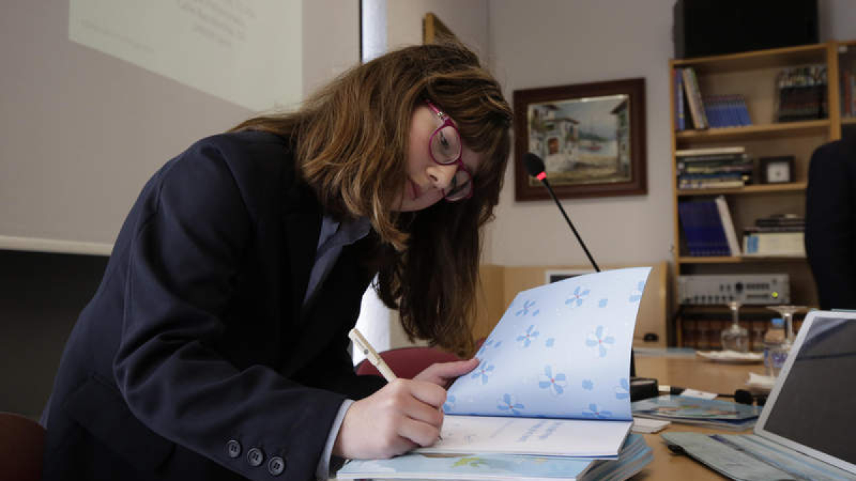 Virginia Mota Sáenz de Miera firma un ejemplar de su cuento tras la presentación este lunes en el Peñacorada.  FERNANDO OTERO