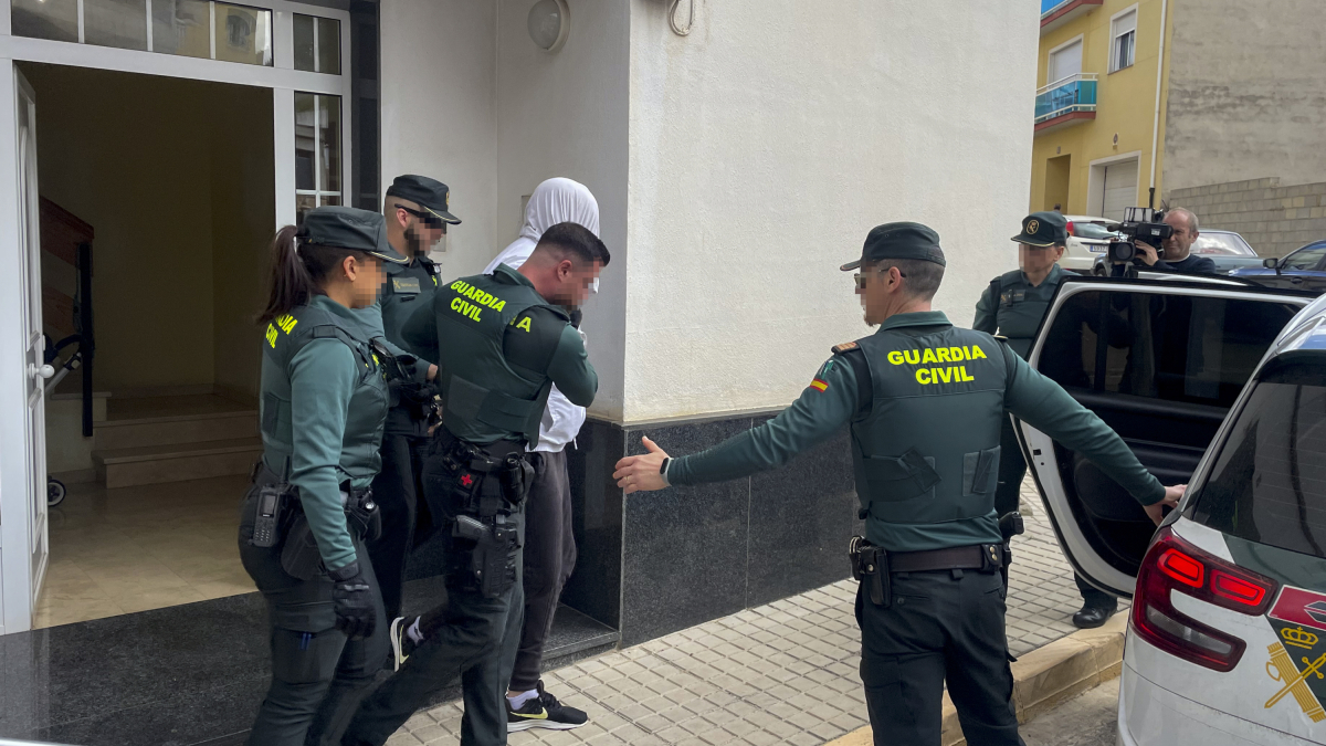 Agentes de la Guardia Civil trasladan a uno de los dos detenidos por el asesinato de una vecina de 65 años del municipio valenciano de Rafelcofer, profesora jubilada.