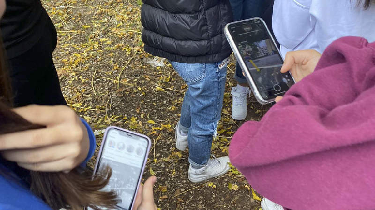 Menores con el móvil en un parque.
