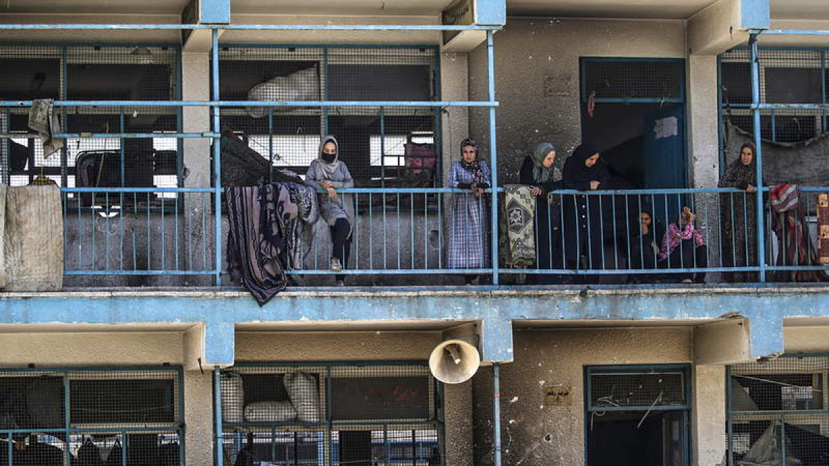 Palestinos desplazados miran desde balcones del edificio atacado por Israel. MOHAMMED SABER
