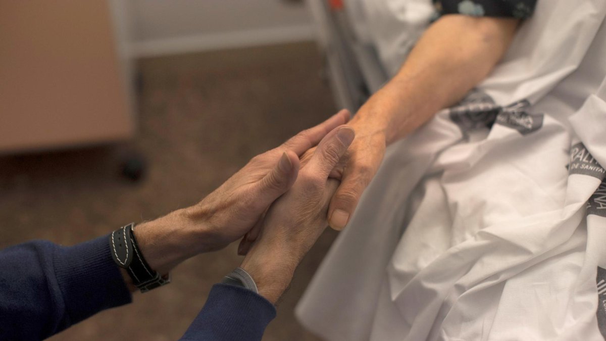 Una mujer es acariciada por su marido minutos antes de que la paciente culmine el proceso para morir por eutanasia, en una imagen de archivo.