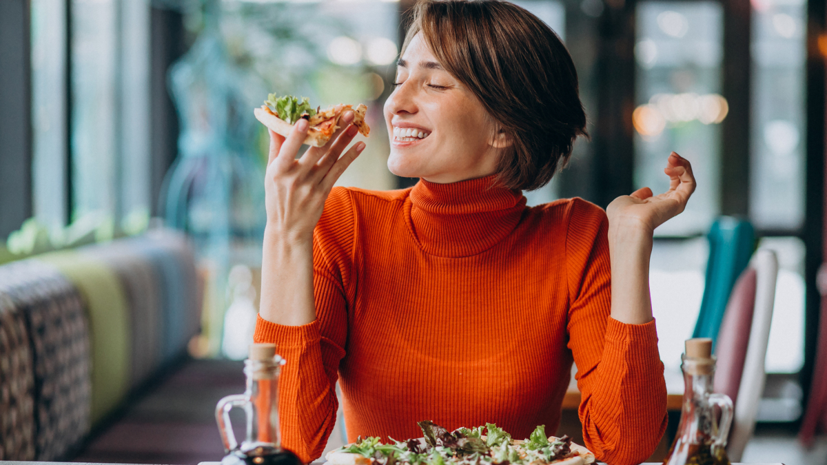 Mujer paladeando una pizza con ingredientes vegetales