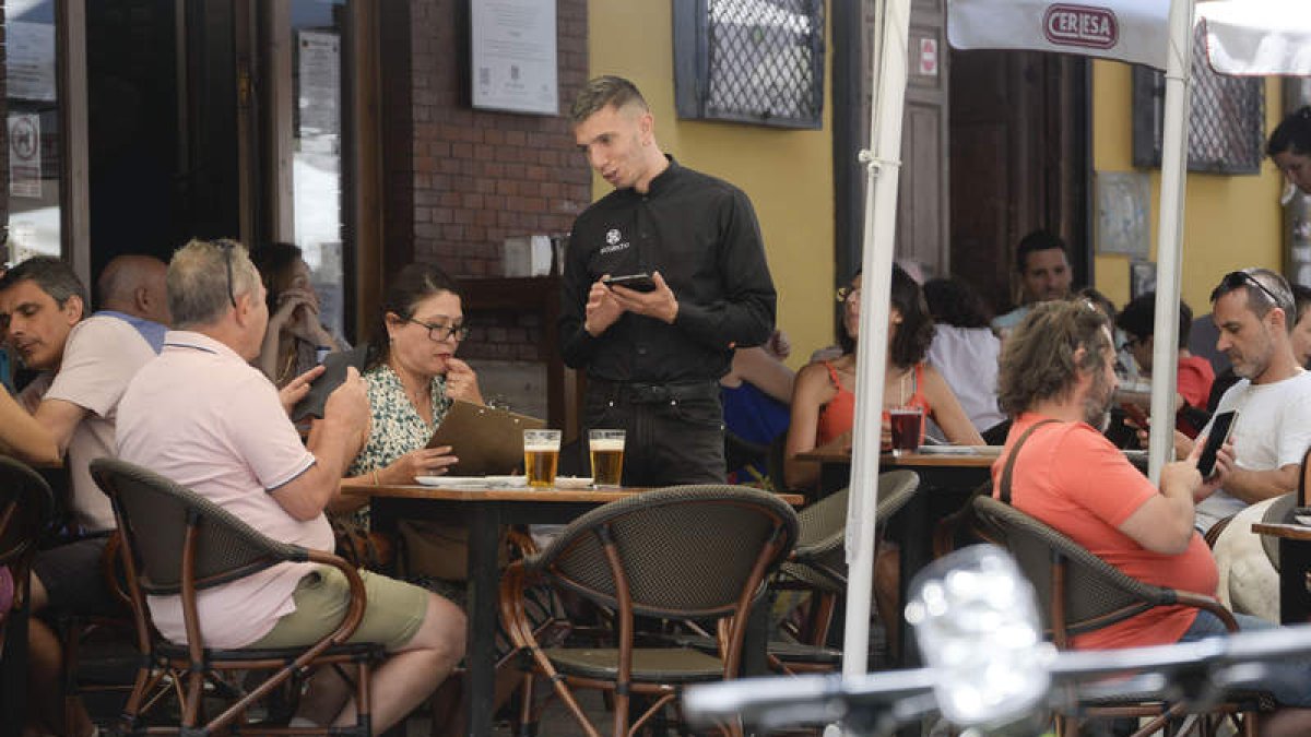 Un camarero atiende a clientes en la terraza del establecimiento en el que trabaja.  MARÍA FUENTES