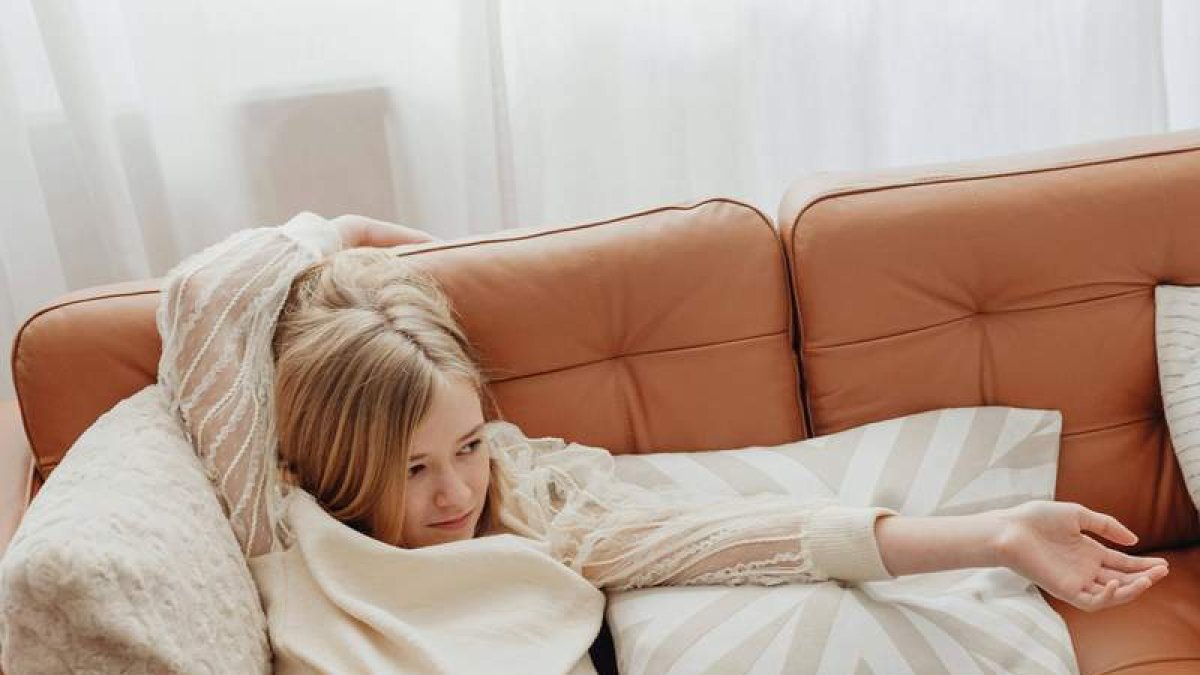 Una niña estirada en un sofá en una foto de archivo. PEXELS