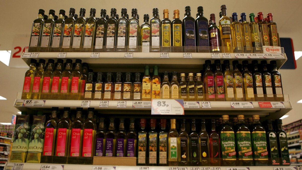 Imagen de archivo de unas estanterías repletas de botellas de aceite de oliva en un supermercado. i