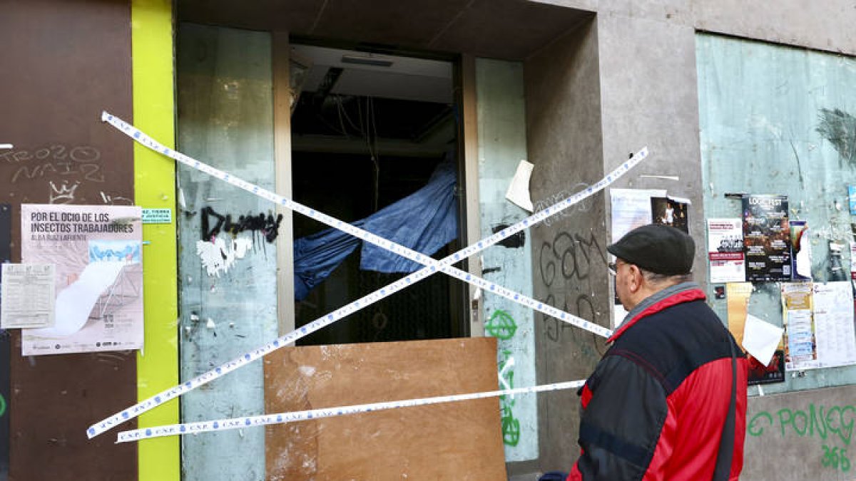 Un peatón se detiene enfrente del cajero donde dos personas que dormían en su interior han fallecido esta madrugada a causa de un incendio