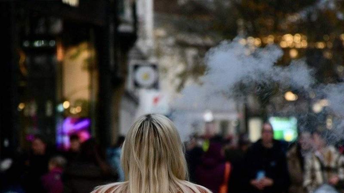 Una mujer vapea mientras camina por la calle. MAYUKH__KARMAKAR