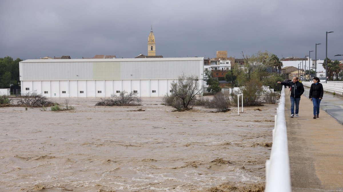 Dos personas contemplan el gran caudal del río Magre a su paso por Alfarp (Valencia) debido a las lluvias torrenciales. EFE/Ana Escobar