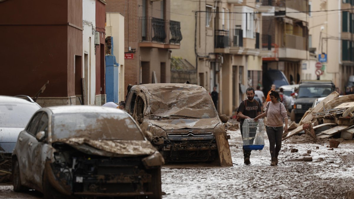 Vecinos de Paiporta trabajan en la limpieza de calles, locales y viviendas de la localidad junto a una montaña de vehículos arrastrados por la corriente, este viernes. Las víctimas mortales en la provincia de Valencia a causa de la devastadora dana ha aumentado este viernes hasta las 205, según el último recuento facilitado por el Centro de Emergencias de la Generalitat Valenciana. EFE/Biel Aliño