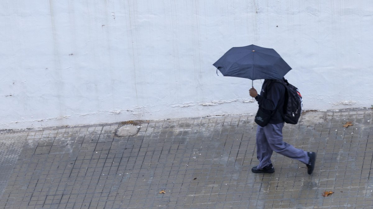 Un joven se protege de la lluvia con un paraguas en Valencia, en una imagen de archivo. EFE/Kai Försterling