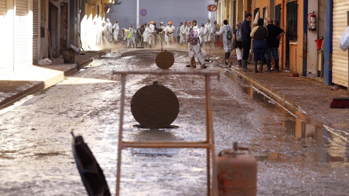 Decenas de voluntarios continuan extrayendo lodo de las calles, este domingo, en la población de l`horta Sud de Catarroja. EFE/Miguel Ángel Polo