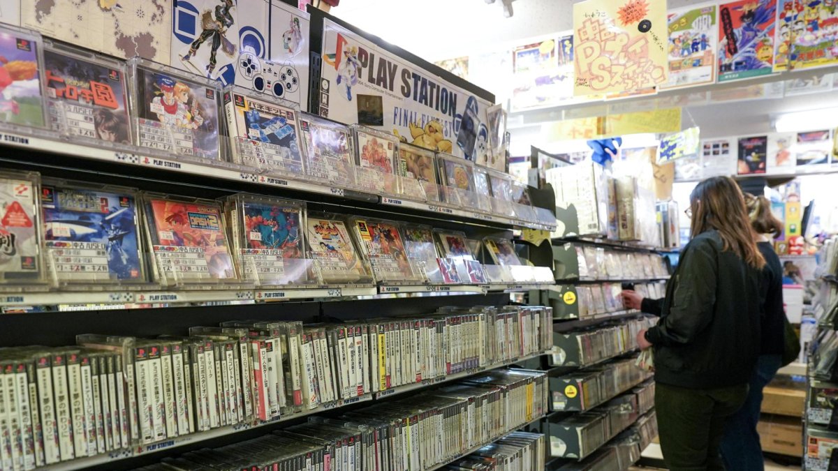 Unas personas frente a una estantería con juegos usados de PlayStation a la venta en una tienda de videojuegos retro en Tokio, el 3 de diciembre de 2024. EFE/EPA/CHRISTOPHER JUE