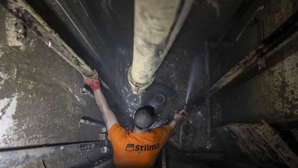 Un trabajador realiza labores de dragado en el hueco de un ascensor averiado por la inundación en Paiporta. EFE/Biel Aliño