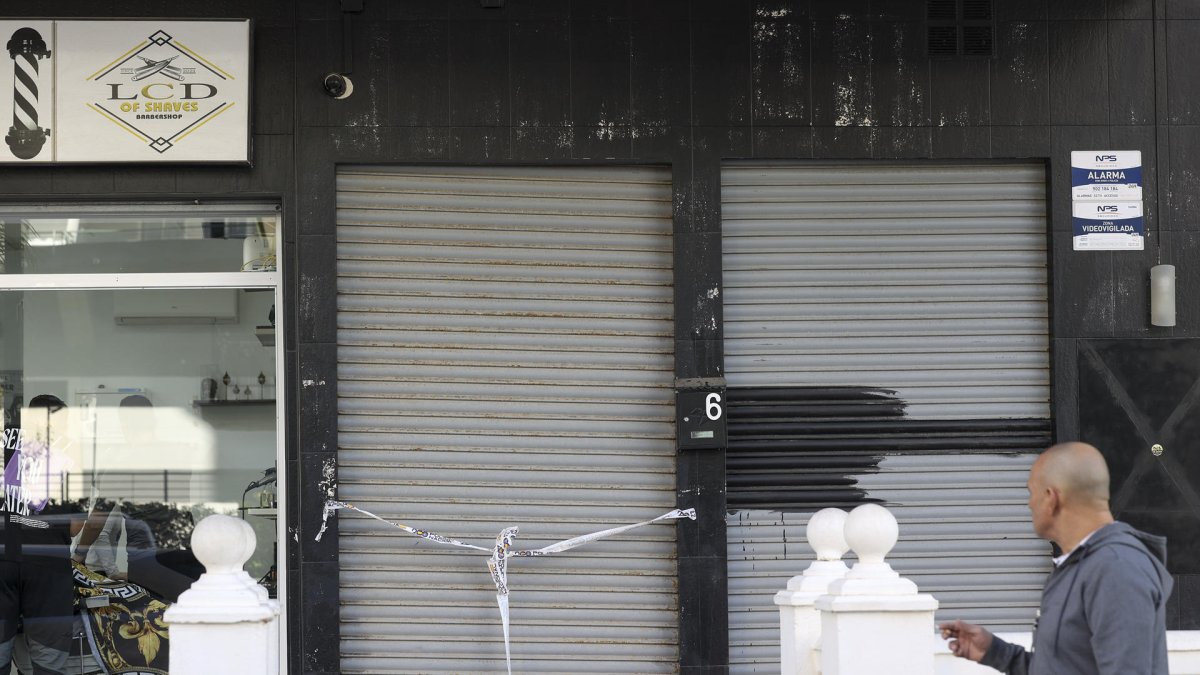 Una persona camina frente a un local precintado por la Policía Nacional en la zona de la localidad de Fuengirola. EFE/Daniel Pérez