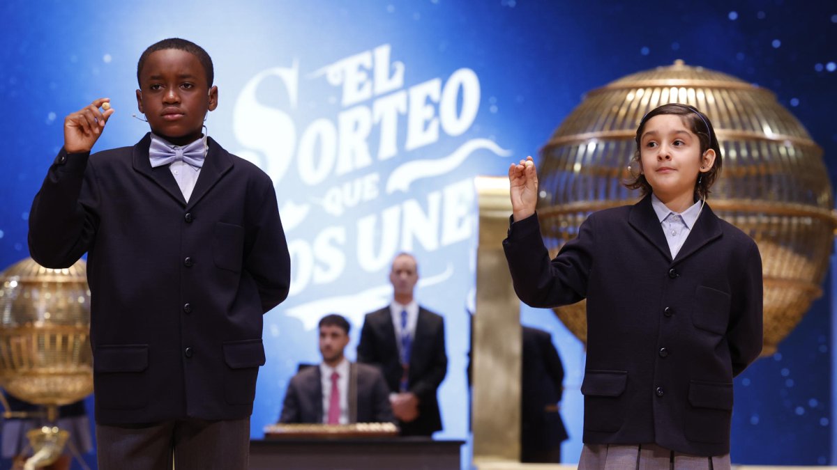 Los niños de la Residencia San Ildefonso de Madrid Ángel Abaga Elebiyo (i) y Aurora Rodríguez Ososrio (d) muestran el número 72.853, uno de los quintos premios, durante el sorteo de la Lotería de Navidad que se celebra este domingo en el Teatro Real, en Madrid. EFE/Javier Lizón