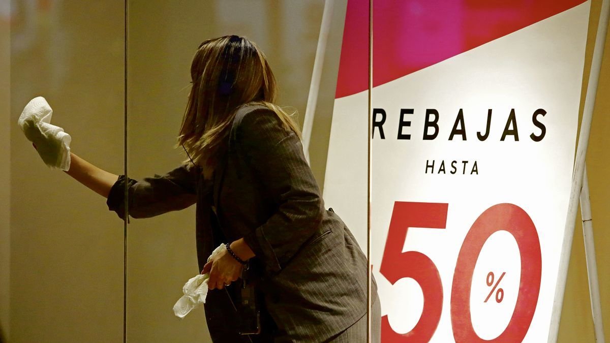 Una dependienta prepara un escaparate que anuncia los descuentos. fernando otero