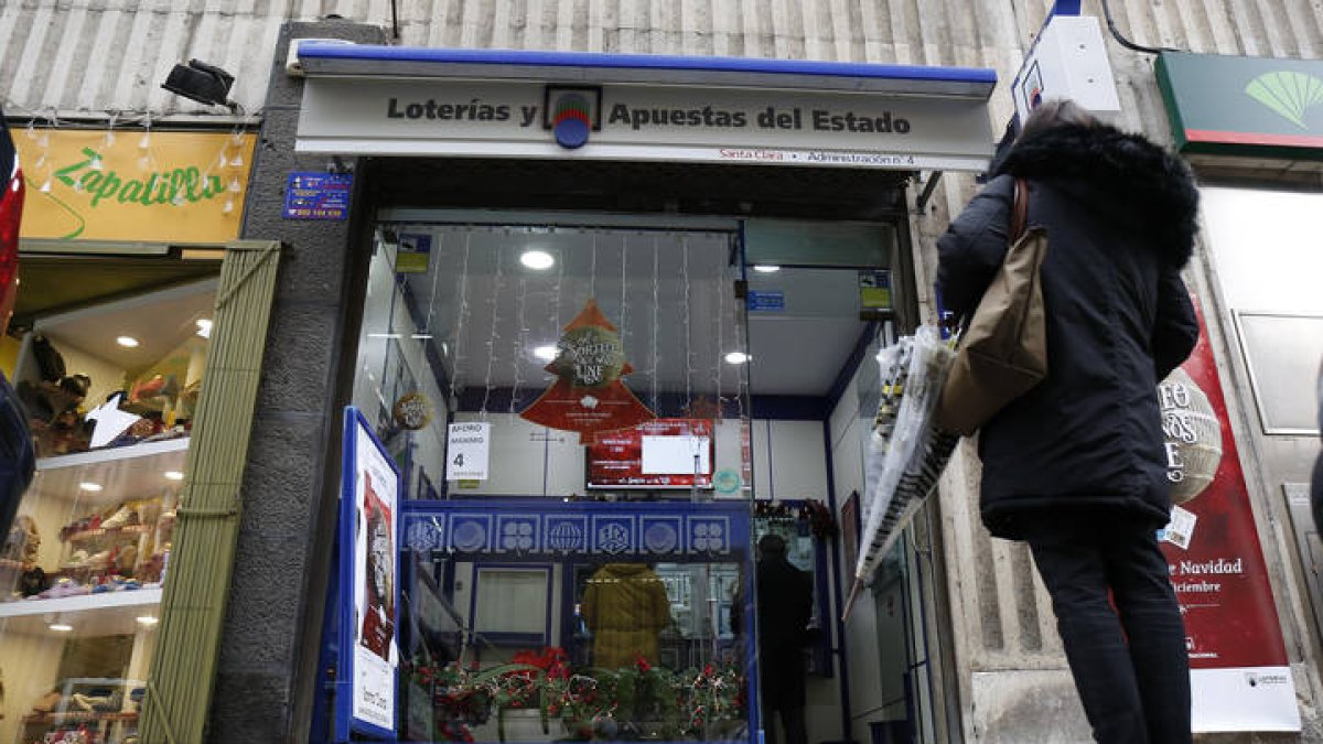 Una persona observa la entrada de una administración de lotería.