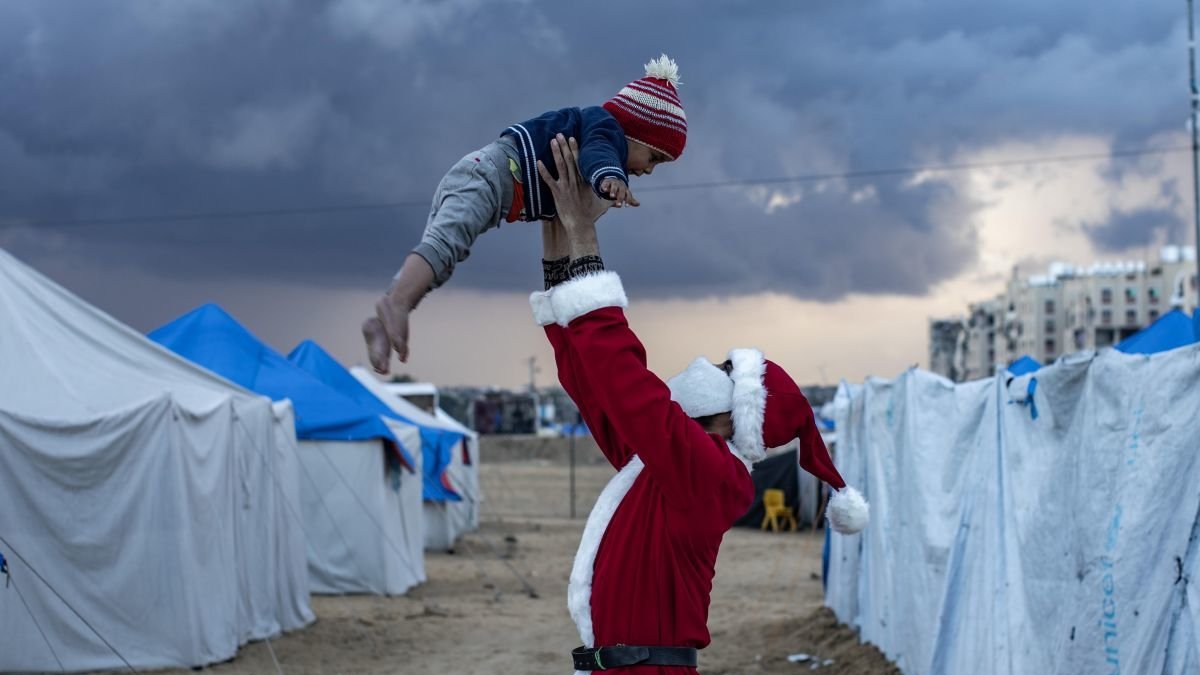 Un desplazado vestido de Papa Noel reparte caramelos entre los niños. haitahm imad
