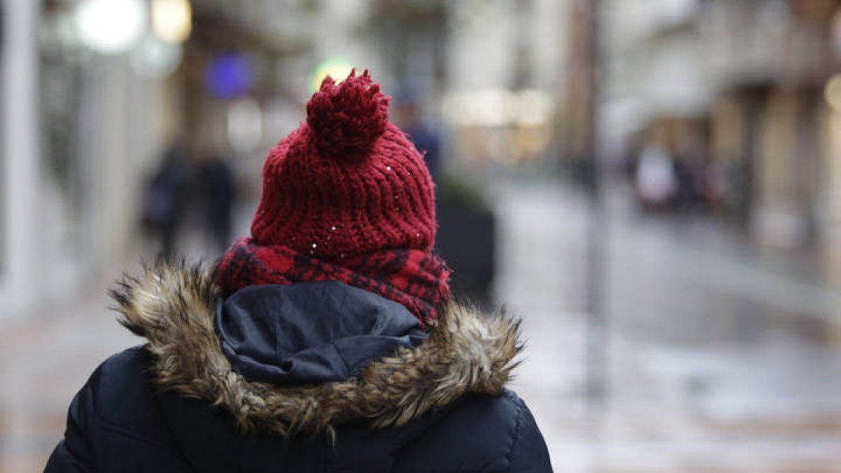 Una persona se protege del frío en la ciudad.