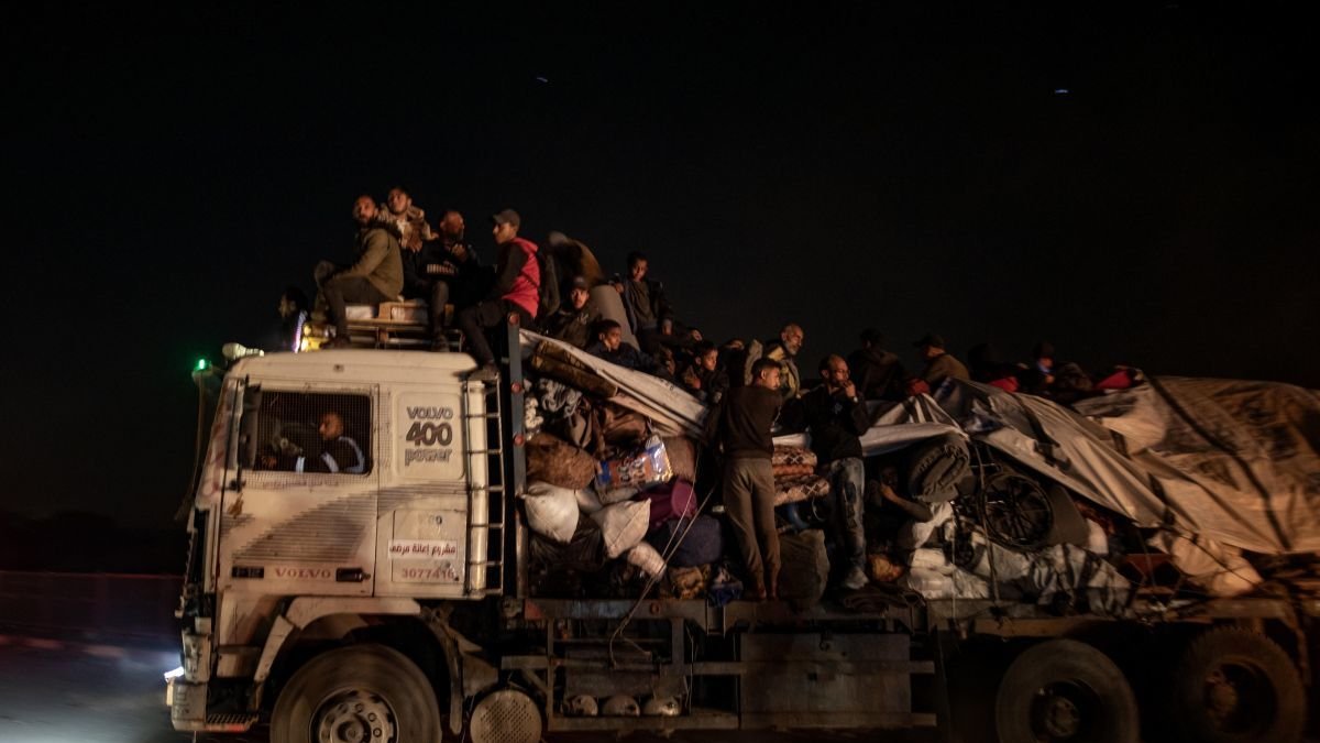 Palestinos desplazados internos viajan durante la noche esperando regresar a sus hogares en el norte de Gaza.
