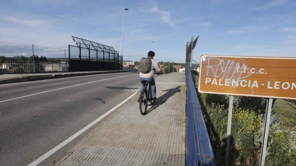 Un ciclista atraviesa el paso superior de Trobajo del Cerecedo sobre las vías.