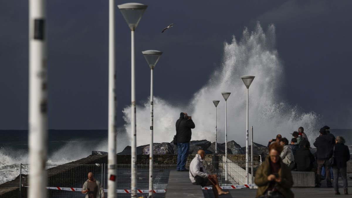 Turistas y donostiarras observan el oleaje en la playa de la Zurriola de San Sebastián.