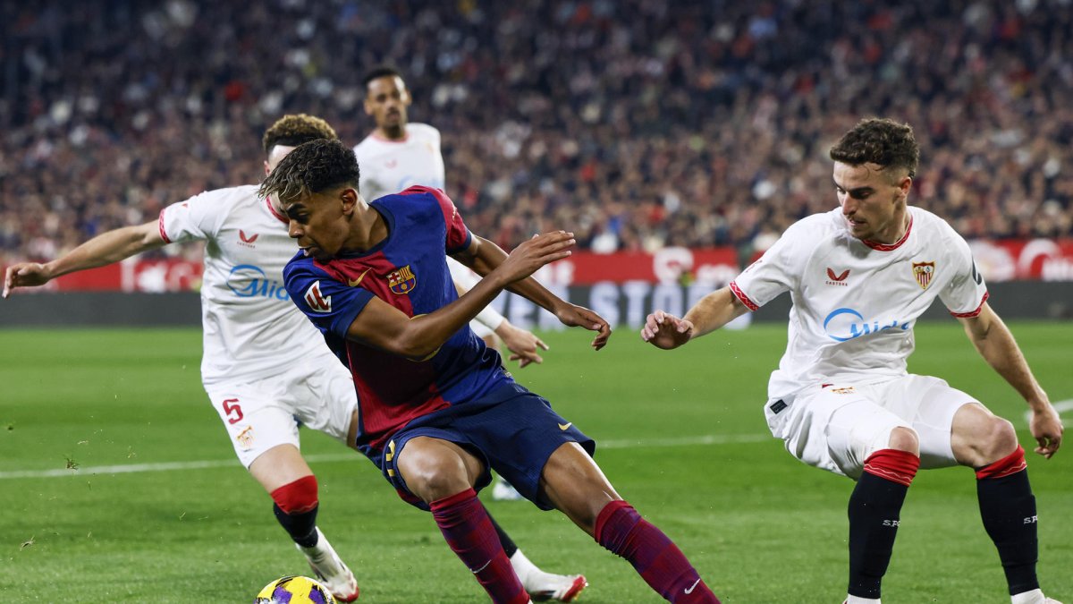 El delantero del FC Barcelona Lamine Yamal (2i)se escapa de la presión de varios jugadores sevillistas durante un encuentro correspondiente a la jornada 23 de LaLiga EA Sports entre el Sevilla FC y el FC Barcelona en el estadioo Ramón Sánchez-Pizjuán de Sevilla. EFE/ Julio Munoz