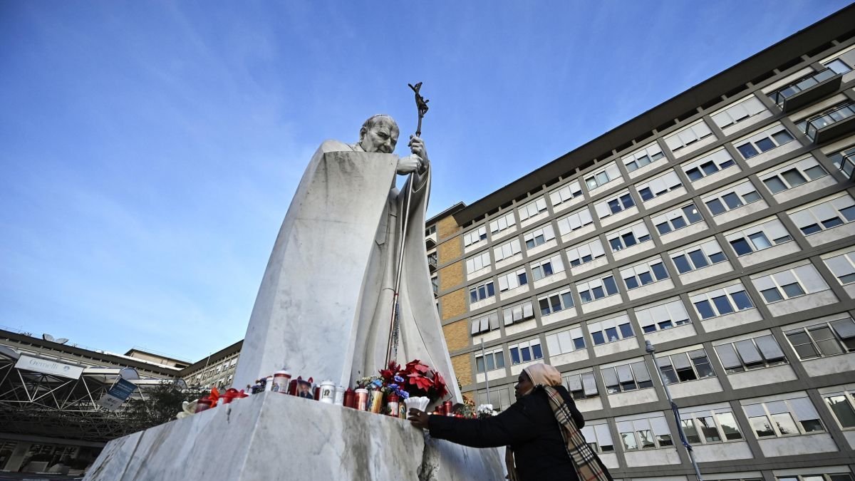Una mujer pone flores en la estatua de Juan Pablo II en el hospital Gemelli.