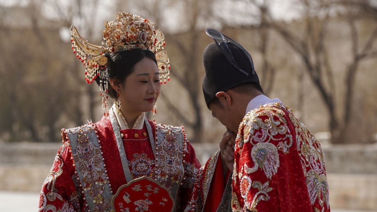 Una pareja con el traje tradicional tras contraer matrimonio ante la ciudad prohibida.