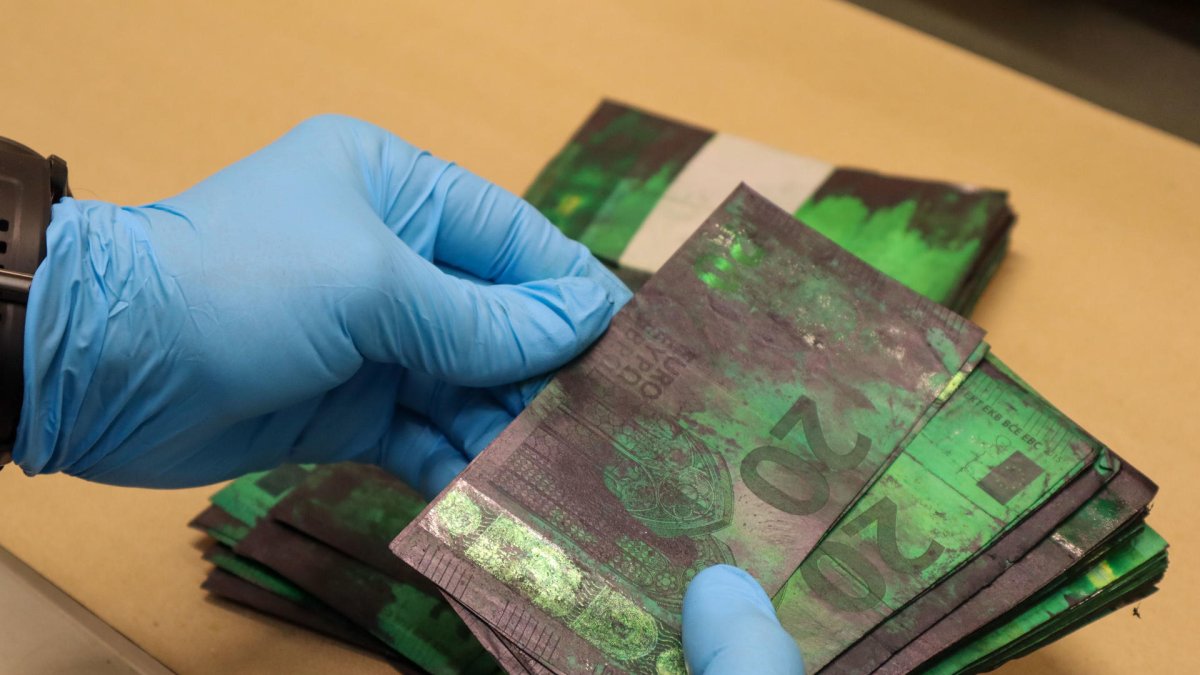 Un trabajador del Área de Operaciones con Efectivo del Banco de Portugal maneja un fajo de billetes de 20 euros manchados de tinta. EFE/Carlos Caselles
